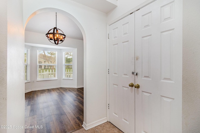 entrance foyer with baseboards, wood finished floors, and a notable chandelier