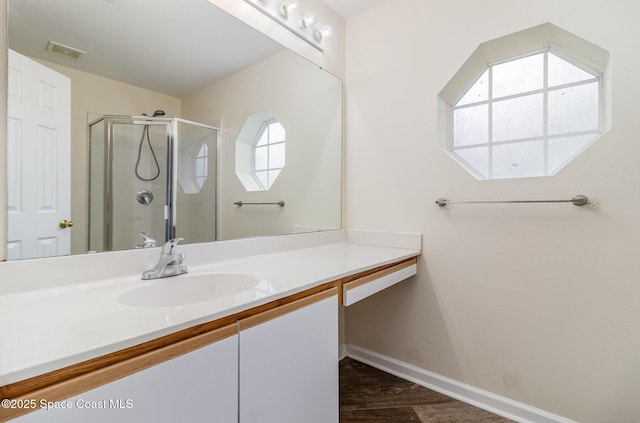 full bath with baseboards, visible vents, wood finished floors, vanity, and a shower stall