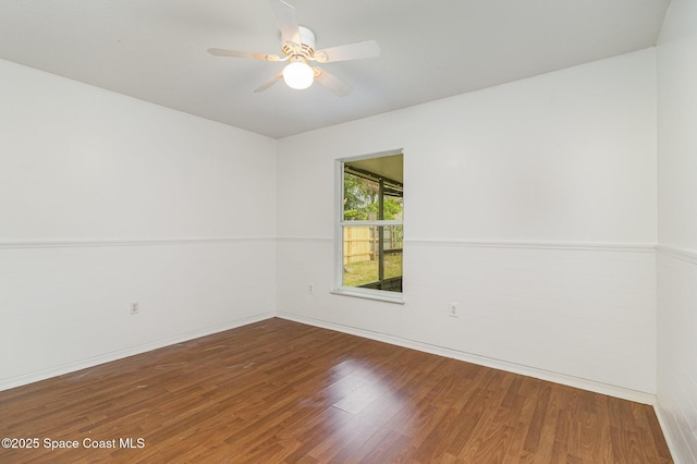 unfurnished room with ceiling fan, a wainscoted wall, and wood finished floors