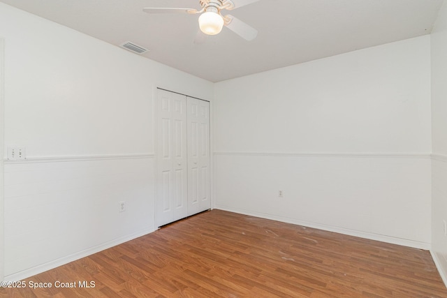 unfurnished bedroom with a ceiling fan, a closet, visible vents, and wood finished floors