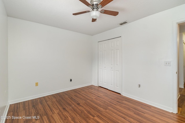 unfurnished bedroom featuring baseboards, visible vents, a ceiling fan, wood finished floors, and a closet