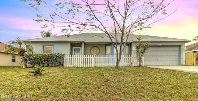 ranch-style house featuring driveway, an attached garage, fence, a front lawn, and stucco siding