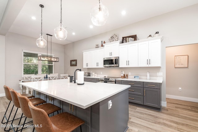 kitchen featuring light wood-type flooring, a spacious island, white cabinets, and stainless steel appliances