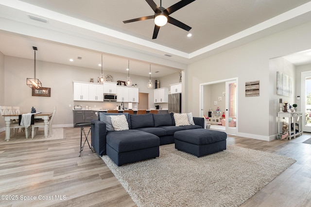 living room featuring light wood finished floors, recessed lighting, visible vents, and baseboards