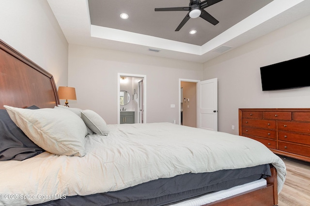 bedroom with light wood finished floors, visible vents, a tray ceiling, and recessed lighting