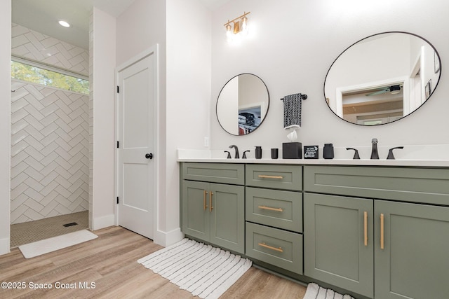 full bathroom with wood finished floors, double vanity, a sink, and a walk in shower