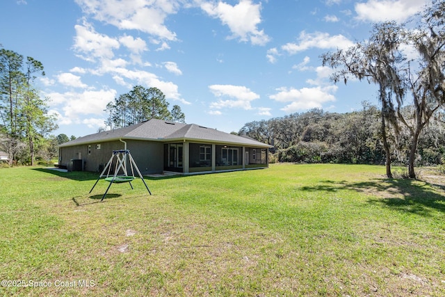 rear view of property with a sunroom, a lawn, and stucco siding