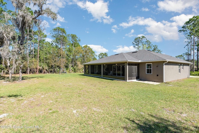 back of property with a sunroom, a lawn, and stucco siding