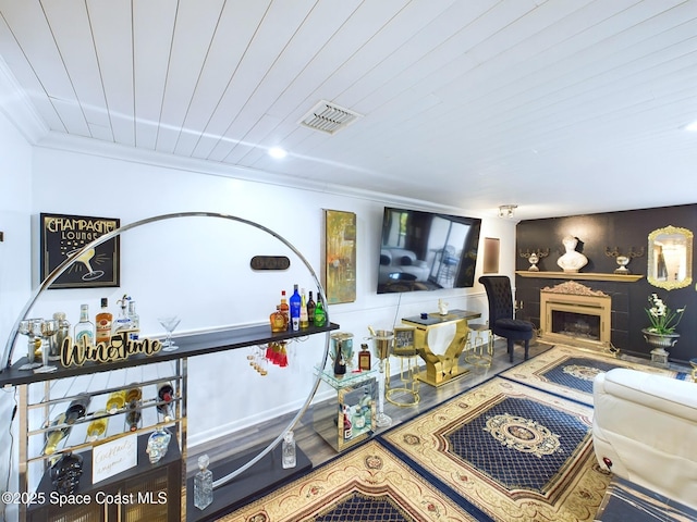 living area with wood ceiling, a fireplace, visible vents, and crown molding