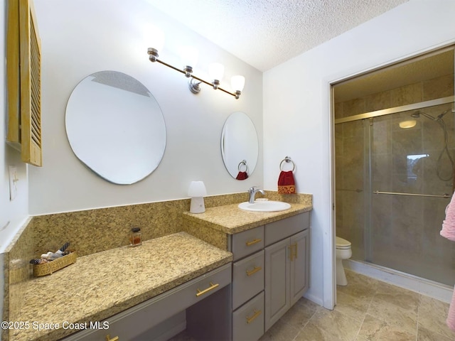 full bath with toilet, a shower stall, a textured ceiling, and vanity