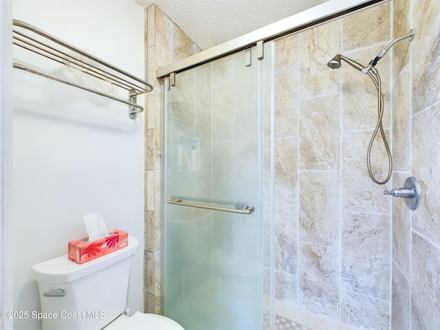 full bath with toilet, a shower stall, and a textured ceiling