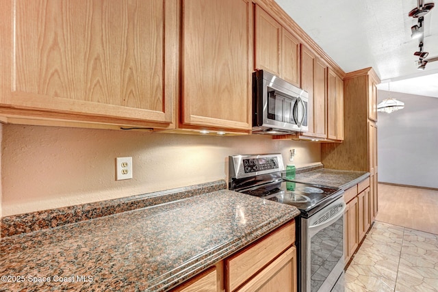 kitchen with marble finish floor, stainless steel appliances, light brown cabinets, dark stone countertops, and track lighting