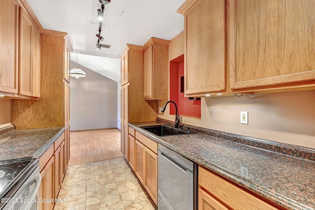 kitchen with stainless steel appliances, dark stone countertops, a sink, and stone finish flooring