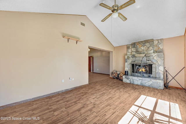 unfurnished living room featuring a fireplace, visible vents, ceiling fan, wood finished floors, and high vaulted ceiling