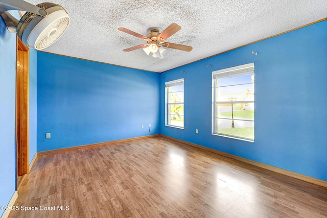 spare room with a ceiling fan, a textured ceiling, baseboards, and wood finished floors