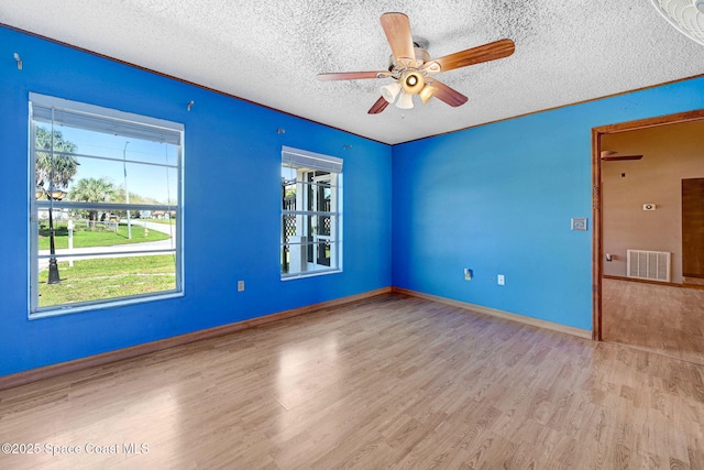 unfurnished room with visible vents, a ceiling fan, a textured ceiling, wood finished floors, and baseboards