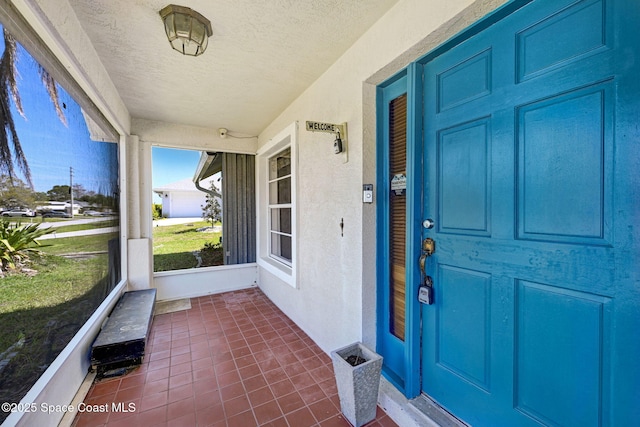 view of exterior entry featuring covered porch and stucco siding