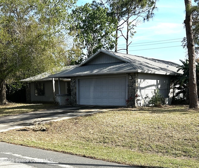 ranch-style home featuring an attached garage, stone siding, driveway, roof with shingles, and a front yard