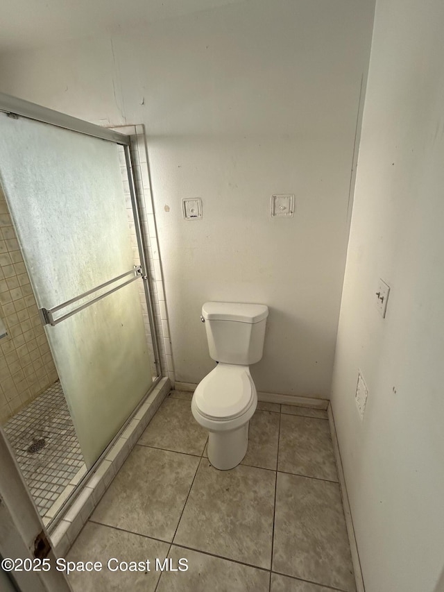 bathroom with a shower stall, tile patterned flooring, toilet, and baseboards