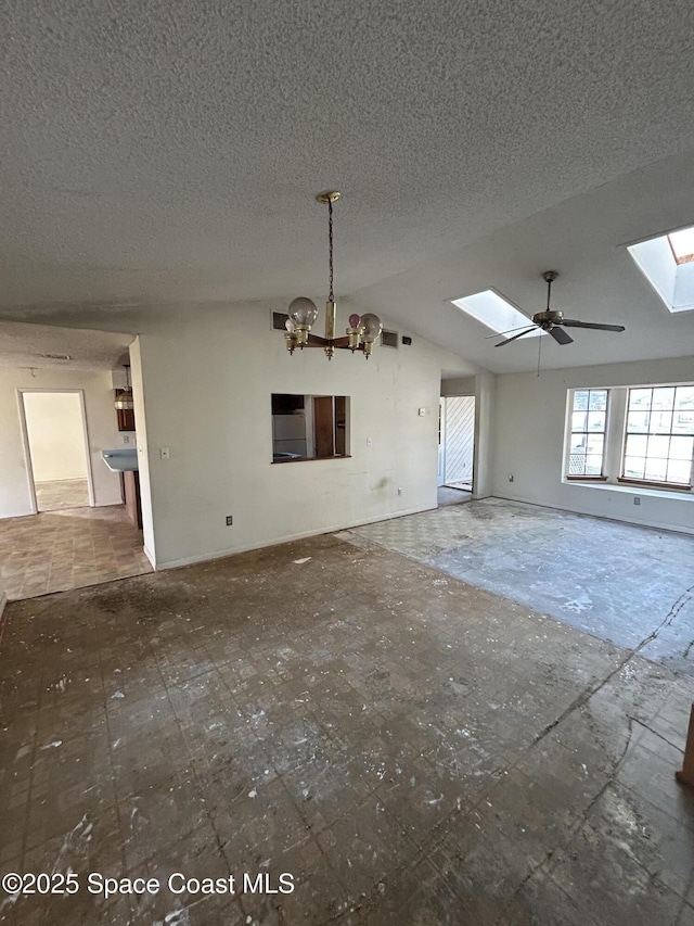 unfurnished living room featuring lofted ceiling with skylight, a textured ceiling, and an inviting chandelier