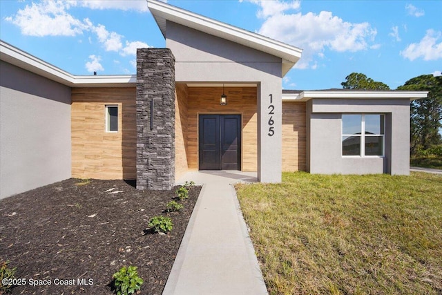 entrance to property with a yard and stucco siding