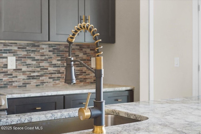 room details with a sink, light stone counters, and gray cabinets