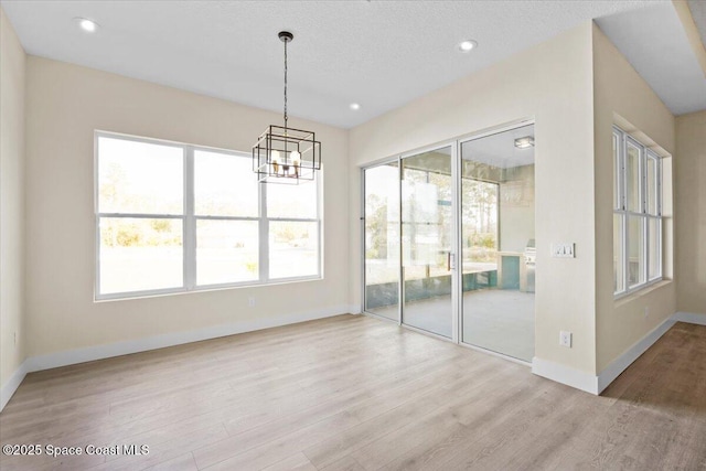 interior space with a chandelier, recessed lighting, light wood-style flooring, and baseboards