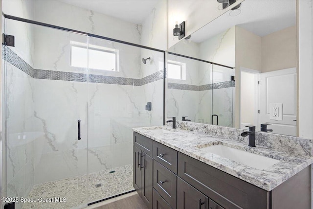 full bathroom featuring double vanity, a marble finish shower, and a sink