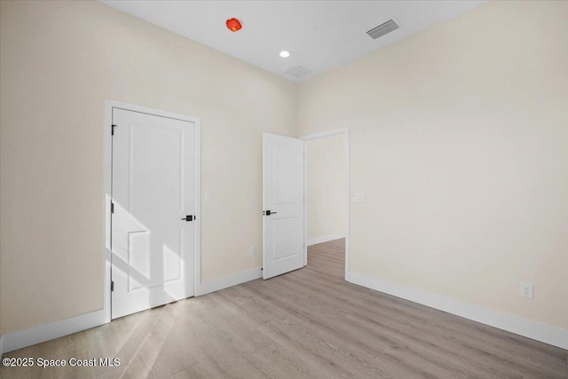 spare room with light wood-type flooring, baseboards, visible vents, and recessed lighting