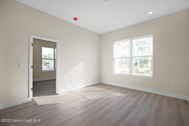 empty room featuring light wood-type flooring, baseboards, and recessed lighting