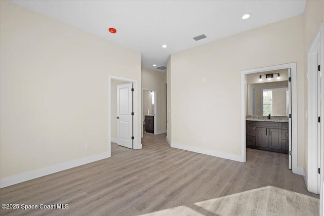 empty room featuring recessed lighting, visible vents, a sink, light wood-type flooring, and baseboards