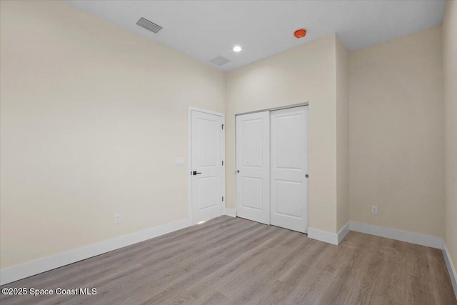 unfurnished bedroom featuring light wood-type flooring, baseboards, visible vents, and a closet