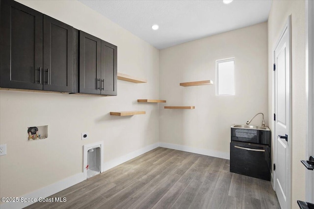 laundry area with hookup for an electric dryer, washer hookup, baseboards, light wood-type flooring, and cabinet space