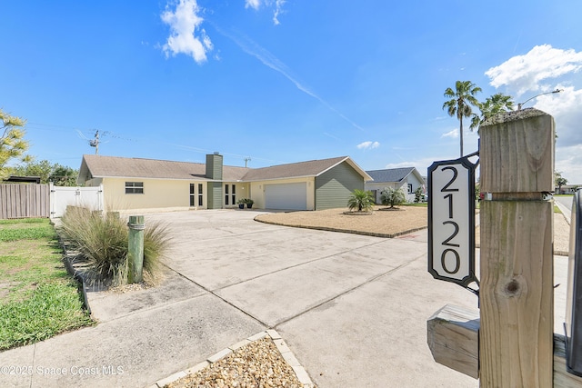 ranch-style home featuring a garage, fence, driveway, a gate, and a chimney