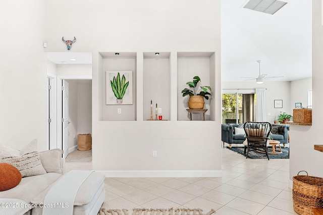 living room featuring light tile patterned floors, visible vents, a towering ceiling, ceiling fan, and baseboards