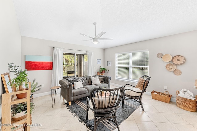 living room featuring a textured ceiling, light tile patterned flooring, a ceiling fan, and baseboards