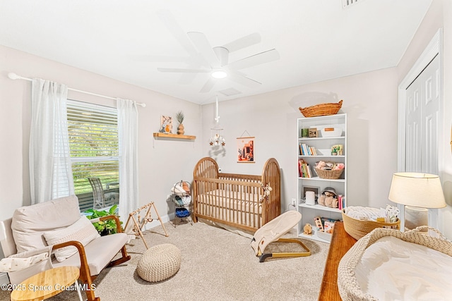 carpeted bedroom featuring a ceiling fan, a nursery area, and baseboards