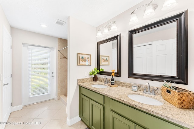 bathroom with a tile shower, a sink, visible vents, and tile patterned floors