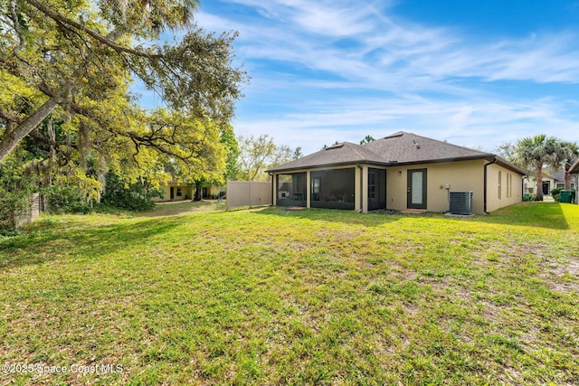 back of property featuring a lawn, a sunroom, fence, central air condition unit, and stucco siding