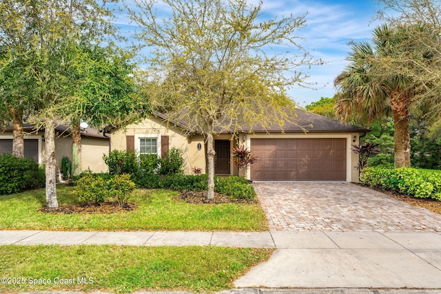 ranch-style house featuring a front yard, decorative driveway, an attached garage, and stucco siding