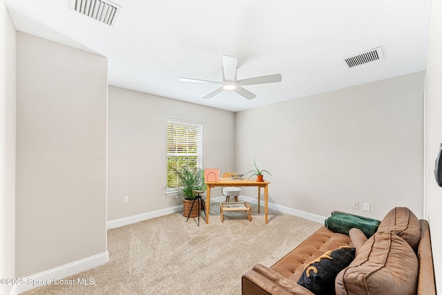 carpeted office space featuring a ceiling fan, visible vents, a textured ceiling, and baseboards