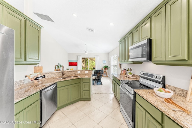 kitchen featuring light tile patterned floors, a peninsula, stainless steel appliances, green cabinets, and a sink