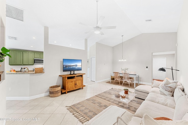 living room featuring ceiling fan with notable chandelier, lofted ceiling, visible vents, and light tile patterned flooring