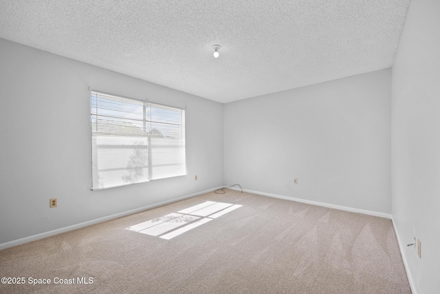 unfurnished room with a textured ceiling, carpet floors, and baseboards