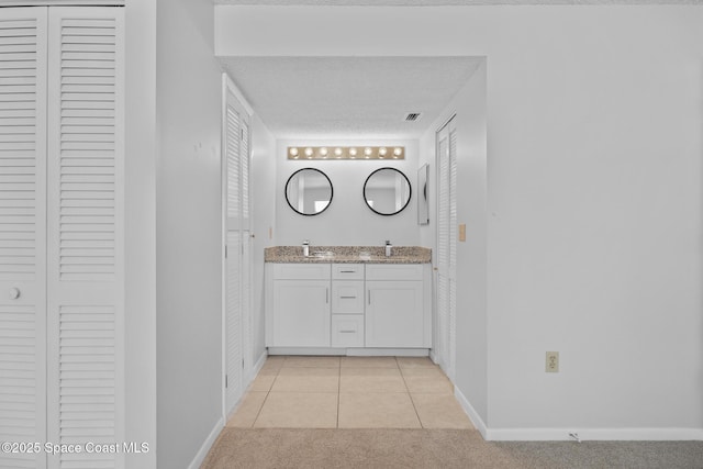 bathroom featuring double vanity, a closet, visible vents, baseboards, and tile patterned floors