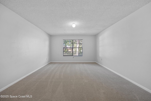 empty room with a textured ceiling, carpet flooring, and baseboards