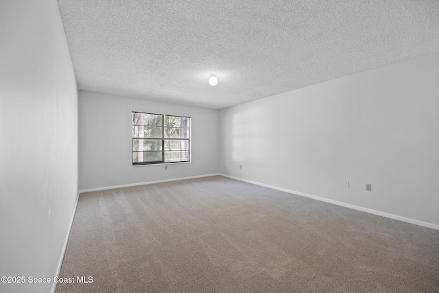 spare room featuring a textured ceiling, carpet, and baseboards