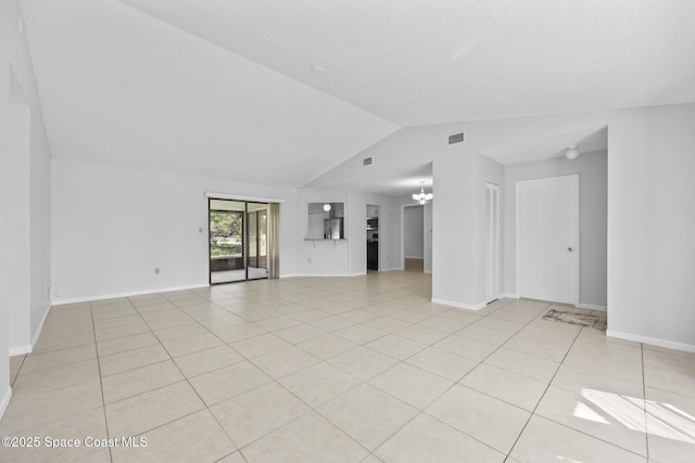 spare room with light tile patterned floors, visible vents, vaulted ceiling, a chandelier, and baseboards