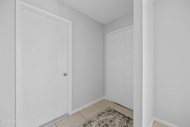 entryway featuring a textured ceiling, light tile patterned flooring, and baseboards