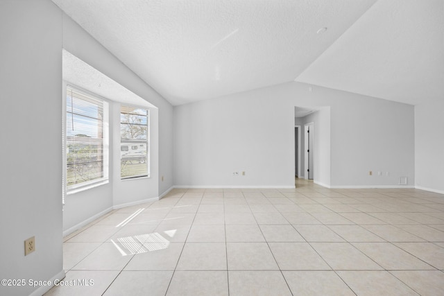 additional living space featuring vaulted ceiling, light tile patterned floors, a textured ceiling, and baseboards